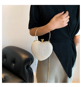 Close-up of heart-shaped glitter clutch bag with golden ring handle and chain strap
