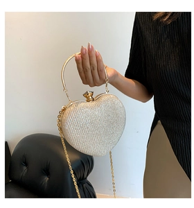 Close-up of heart-shaped glitter clutch with gold ring handle and sleek chain strap