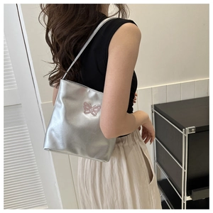Detail of silver faux leather shoulder bag featuring a pink butterfly embroidery