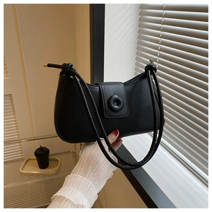 Detail of a black crescent shoulder bag with a round buckle and knotted strap detail