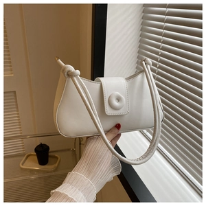Detail of white baguette bag with distinctive disc buckle and knot shoulder strap detail