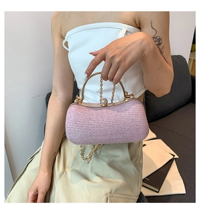 Close-up of pink woven evening bag with golden circular handle and diamond-studded clasp