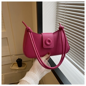 Detail of rose red shoulder bag featuring smooth synthetic leather and round button buckle