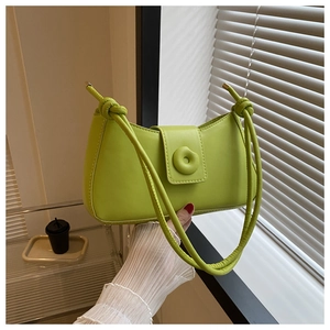 Detail of green shoulder bag featuring a unique doughnut clasp and knot strap design