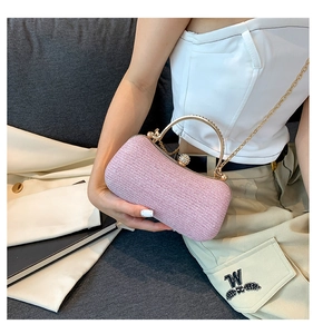 Detail of pink pearl-texture handbag with curved gold handle and luxury chain strap