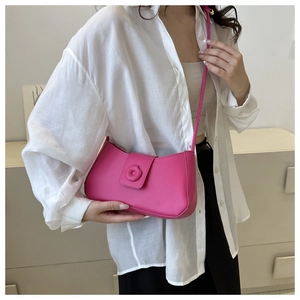 Detail of rose pink leather underarm bag with circular buckle on white shirt