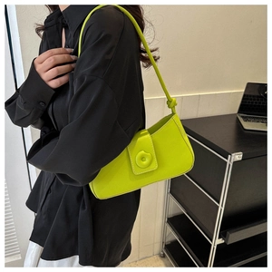 Neon green baguette shoulder bag with circular clasp shown on a black silk shirt