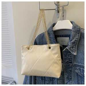 Détail du sac fourre-tout matelassé beige avec chaînes dorées et texture de losanges