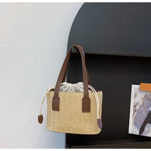 Detail of hand-woven straw bucket bag with leather handles and drawstring inner pouch