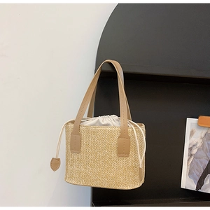 Detail of woven straw handbag with drawstring lining and leather handles on black stand