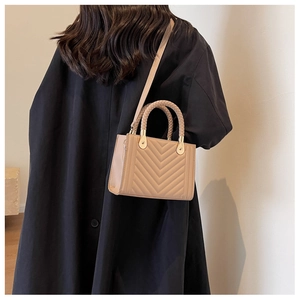 Chic beige chevron quilted crossbody bag shown with woven handle on a black coat outfit