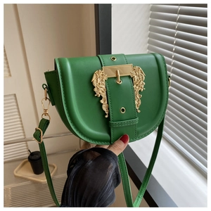 Detailed close-up of green PU leather saddle bag with golden baroque relief buckle