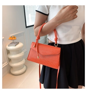 Vue détaillée du sac à main orange plissé avec texture gaufrée et fermoir en métal doré