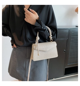 Détail du sac bandoulière blanc crème avec texture plissée et poignée nouée sur modèle