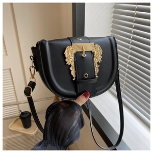 Close-up of black leather saddle bag with ornate gold baroque buckle and slim strap