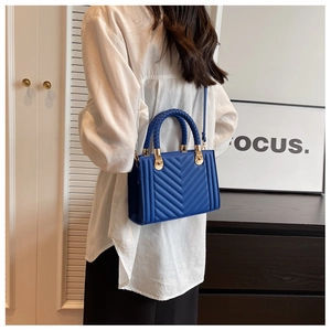 Blue quilted leather bag with woven handle and gold hardware on model in modern setting