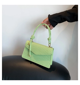 Détail d'un sac à main vert menthe avec texture plissée verticale et accents métalliques