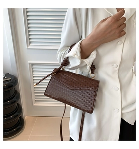 Détail du sac bandoulière plissé marron foncé avec poignée torsadée et accents dorés