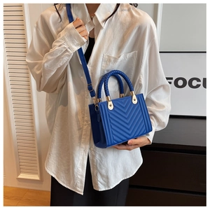 Blue chevron quilted small square bag with woven handles and golden hardware shown on model