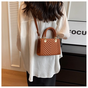 Brown quilted crossbody bag with braided handle and adjustable leather strap shown on model