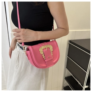 Fashionable rose pink saddle bag with ornate gold baroque buckle worn by a model