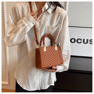 Detailed view of caramel brown crossbody bag with V-quilted pattern and woven handles