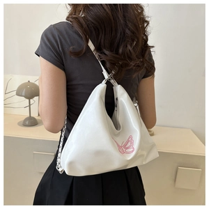 Detail der weißen Hobo-Tasche mit rosa Schmetterlingsstickerei und edlem Metallkettenriemen