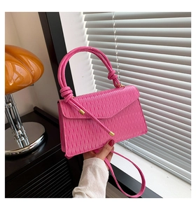 Détail de la texture plissée rose vif et du rabat magnétique sur le petit sac
