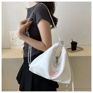 Detail of white slouchy hobo bag featuring delicate pink butterfly embroidery and chain strap