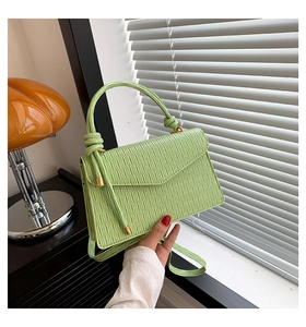 Détail d'un sac à main plissé vert clair avec poignée nouée et textures élégantes