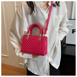 Close-up of rose red quilted crossbody bag with woven ring handle and gold hardware
