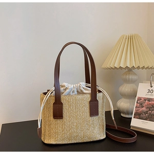 Close-up of woven straw bag with leather handles and beige drawstring inner lining