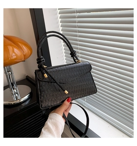 Détail du sac à main noir plissé avec poignée ronde et accents métalliques dorés
