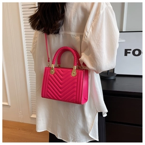 Model wearing a magenta chevron quilted crossbody bag with woven handle and gold hardware