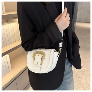 Detail of white saddle bag with golden baroque buckle and slim shoulder strap