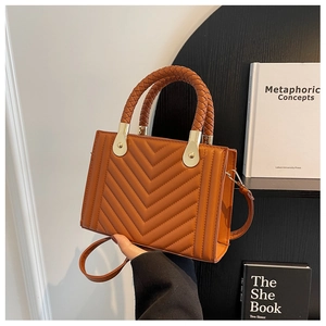 Close-up of caramel brown quilted handbag featuring V-pattern stitching and gold hardware