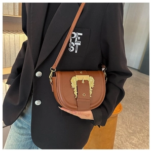 Detailed view of brown leather saddle bag with vintage golden baroque buckle on model