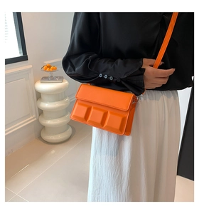 Detail van oranje crossbodytas met 3D-kubuspatroon en mat PU-lederen textuur