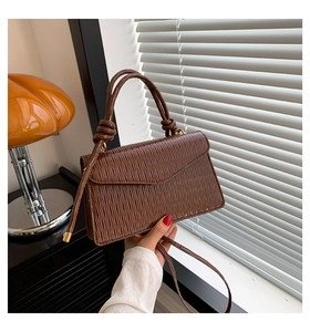 Détail d'un sac à main en cuir plissé marron foncé avec poignées nouées et bandoulière