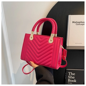 Detailed hot pink quilted bag with woven handle and gold hardware in hand
