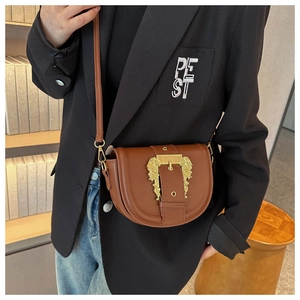 Detailed view of vintage brown leather saddle bag with ornate gold relief buckle
