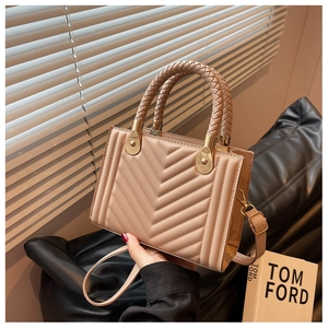 Detail of chevron quilted handbag with woven handle and elegant gold hardware