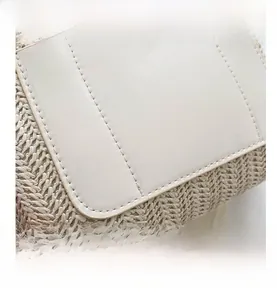 Détail d'un sac seau en paille tressée beige avec bordure en cuir crème et coutures