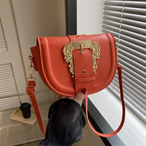 Vibrant orange leather saddle bag with ornate gold buckle and adjustable strap
