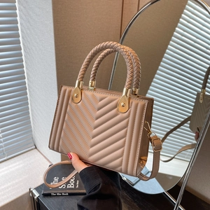 Chic quilted beige crossbody bag with woven handle and gold hardware in minimalist scene