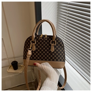 Detail van retro schelptas met monogrampatroon en luxe gouden dubbele ritssluitingen