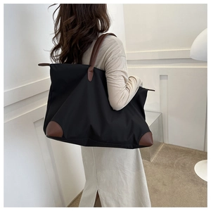 Detailaufnahme der schwarzen Oxford-Reisetasche mit braunem Ledergriff und Bodenschutz