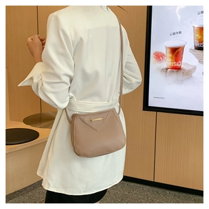 Detail of light brown crossbody bag featuring golden bar hardware and slim shoulder strap