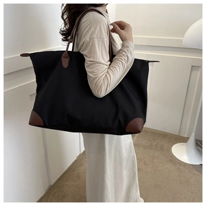 Seitenansicht eines großen schwarzen Nylon-Shoppers mit braunen Lederdetails am Model