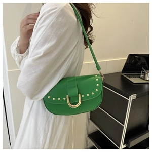 Détail du sac selle vert avec clous dorés et boucle métallique en U sur le rabat
